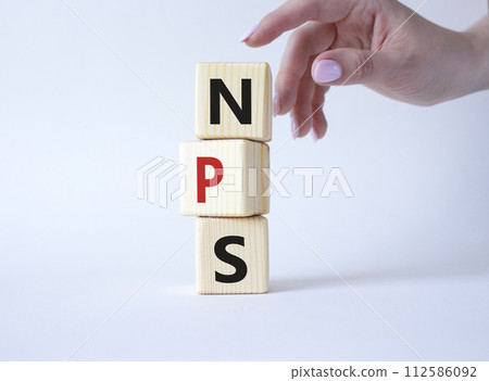 NPS - Net Promoter Score symbol. Wooden cubes with words NPS. Businessman hand. Beautiful white background. Business and NPS concept. Copy space. NPS - Net Promoter Score symbol. Wooden cubes with words NPS. Businessman hand. Beautiful white background. Business and NPS concept. Copy space. 112586092