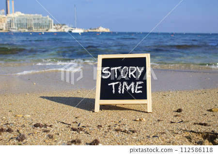 Story Time symbol. Concept word Story Time on black chalk background. Beautiful sea background. Business and Story Time concept. Copy space 112586118