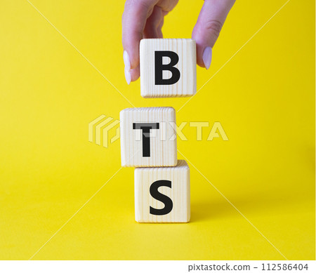 BTS symbol. Wooden cubes with word BTS. Businessman hand Beautiful yellow background. BTS concept. Copy space. 112586404