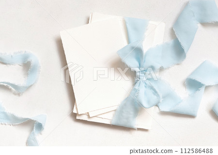 Cards tied with a light blue ribbons on white table top view, copy space, wedding stationery mockup 112586488