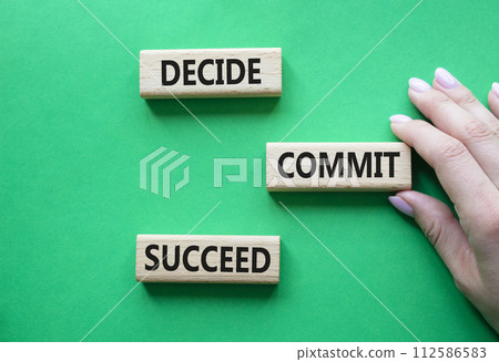 Decide Commit Succeed symbol. Concept words Decide Commit Succeed on wooden blocks. Businessman hand. Beautiful green background. Business concept. Copy space. 112586583