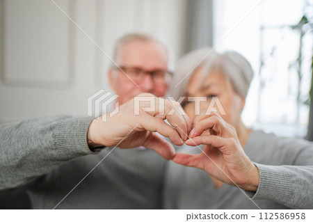 Love heart shape peace. Senior older couple making heart shape with their hands. Adult mature old husband wife showing heart sign. Happy pensioner family. I love you happy valentines day 112586958