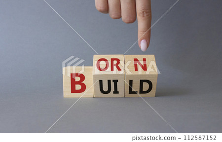 Born and Build symbol. Businessman hand points at turned wooden cubes with words Build to Born. Beautiful grey background. Business and Born and Build concept. Copy space. Born and Build symbol. Businessman hand points at turned wooden cubes with words Build to Born. Beautiful grey background. Business and Born and Build concept. Copy space. 112587152