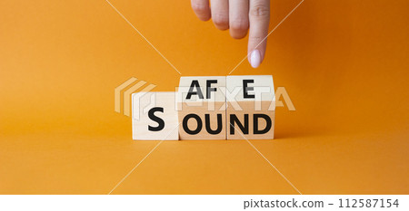 Safe and Sound symbol. Businessman hand points at cubes with words Safe and Sound. Beautiful orange background. Business and Safe and Sound concept. Copy space Safe and Sound symbol. Businessman hand points at cubes with words Safe and Sound. Beautiful orange background. Business and Safe and Sound concept. Copy space 112587154