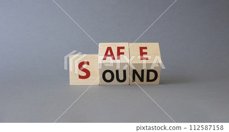 Safe and Sound symbol. Turned wooden cubes with words Safe and Sound. Beautiful grey background. Business and Safe and Sound concept. Copy space 112587158