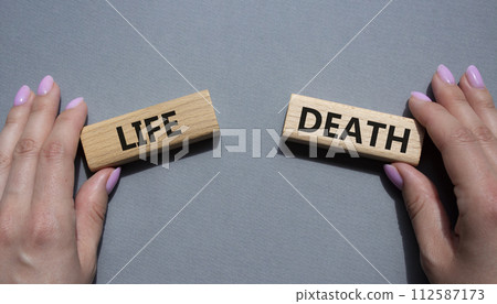 Life or Death symbol. Concept word Life or Death on wooden blocks. Businessman hand. Beautiful grey background. Business and Life or Death concept. Copy space 112587173