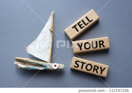 Tell your story symbol. Wooden blocks with words Tell your story. Beautiful grey background with boat. Business and Tell your story concept. Copy space. Tell your story symbol. Wooden blocks with words Tell your story. Beautiful grey background with boat. Business and Tell your story concept. Copy space. 112587206