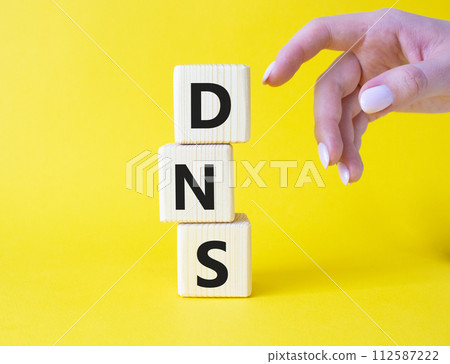DNS -Domain Name Server - Consumer Price Index symbol. Concept word DNS on wooden cubes. Businessman hand. Beautiful yellow background. Business and DNS concept. Copy space. DNS -Domain Name Server - Consumer Price Index symbol. Concept word DNS on wooden cubes. Businessman hand. Beautiful yellow background. Business and DNS concept. Copy space. 112587222