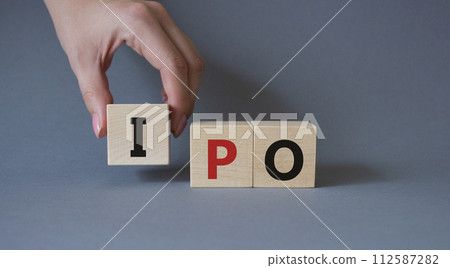 IPO- Initial Public Offering symbol. Concept word IPO on wooden cubes. Businessman hand. Beautiful grey background. Business and IPO concept. Copy space. IPO- Initial Public Offering symbol. Concept word IPO on wooden cubes. Businessman hand. Beautiful grey background. Business and IPO concept. Copy space. 112587282