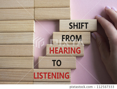 Listening symbol. Wooden blocks with words Shift from Hearing to Listening. Businessman hand. Beautiful pink background. Business and Listening concept. Copy space. Listening symbol. Wooden blocks with words Shift from Hearing to Listening. Businessman hand. Beautiful pink background. Business and Listening concept. Copy space. 112587333