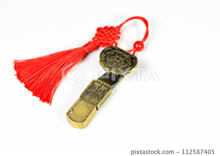 Traditional chinese brass amulet as presents. Chinese style amulet with red decorative good luck knots means good fortune, happiness and rich on white background. Traditional chinese brass amulet as presents. Chinese style amulet with red decorative good luck knots means good fortune, happiness and rich on white background. 112587405