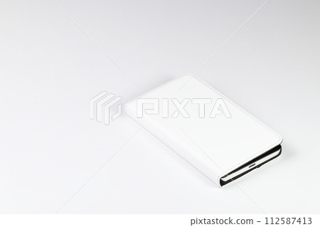 Mobile phone or smart phone in white leather case on white background. Mobile phone or smart phone in white leather case on white background. 112587413
