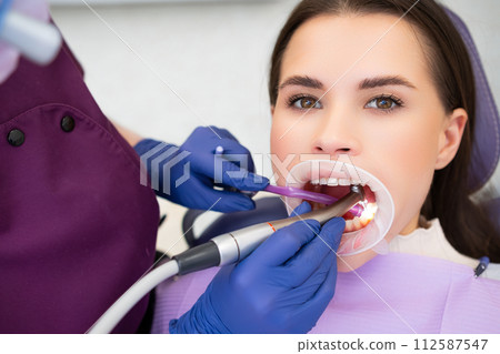 Young beautiful woman undergoes tooth filling in dentists office Young beautiful woman undergoes tooth filling in dentists office 112587547