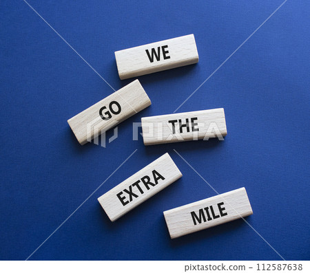 We go the extra mile symbol. Wooden blocks with words We go the extra mile. Beautiful deep blue background. Business and We go the extra mile concept. Copy space. 112587638