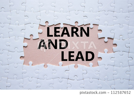Learn and lead symbol. Concept words Learn and lead on white puzzle. Beautiful pink background. Business and Learn and lead concept. Copy space. 112587652