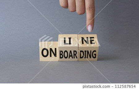 Online Onboarding symbol. Businessman Hand points at turned wooden cubes with words Online Onboarding. Beautiful grey background. Business and Online Onboarding concept. Copy space 112587654