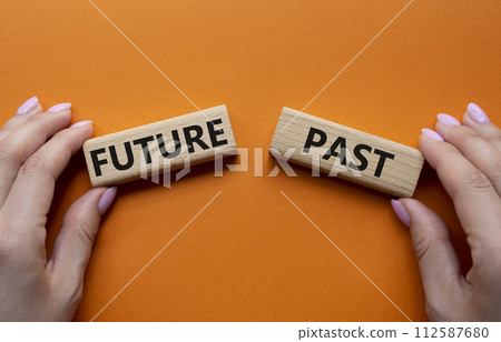 Future or Past symbol. Concept word Future or Past on wooden blocks. Businessman hand. Beautiful orange background. Business and Future or Past concept. Copy space 112587680