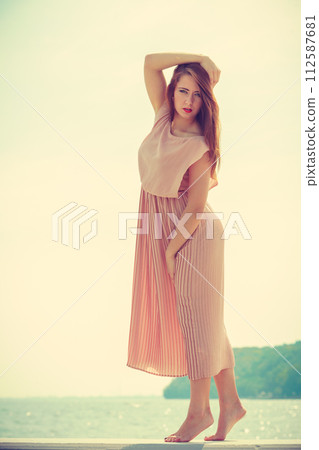 Woman wearing long light pink dress on jetty 112587681