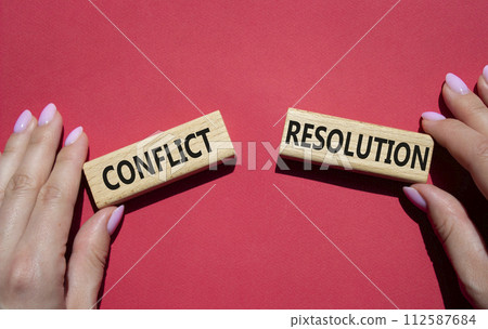 Conflict or Resolution symbol. Concept word Conflict or Resolution on wooden blocks. Businessman hand. Beautiful red background. Business and Conflict or Resolution concept. Copy space 112587684