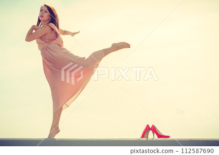 Woman dancing wearing long light pink dress Woman dancing wearing long light pink dress 112587690