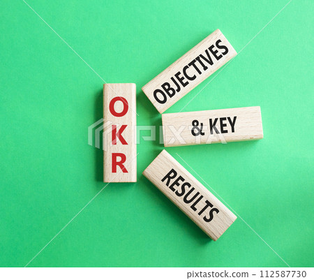 OKR objectives and key results symbol. Wooden blocks with words OKR objectives and key results. Beautiful green background. Business and OKR concept. Copy space. 112587730