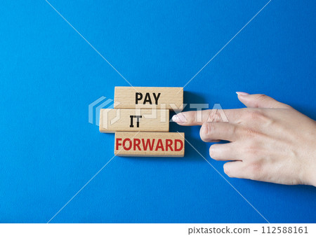 Pay it forward symbol. Concept words Pay it forward on wooden blocks. Beautiful blue background. Businessman hand. Business and Pay it forward concept. Copy space. Pay it forward symbol. Concept words Pay it forward on wooden blocks. Beautiful blue background. Businessman hand. Business and Pay it forward concept. Copy space. 112588161