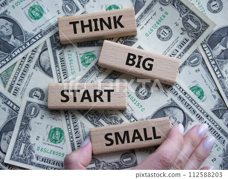 Think big start small symbol. Concept words Think big start small on wooden blocks. Beautiful dollar background. Businessman hand. Business and Think big start small concept. Copy space 112588203