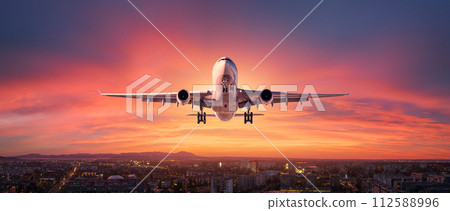 Airplane is flying in colorful sky over the city at night Airplane is flying in colorful sky over the city at night 112588996