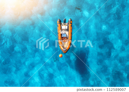 Aerial view of beautiful orange boat in blue sea at sunset Aerial view of beautiful orange boat in blue sea at sunset 112589007