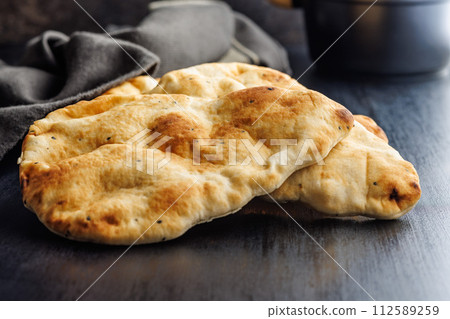 Freshly Baked Naan Bread Resting on a Dark Wooden Table 112589259