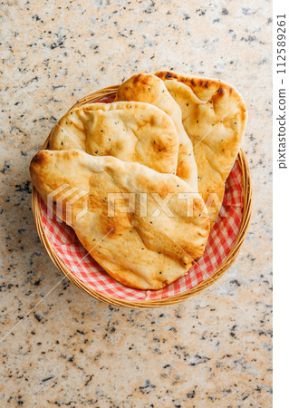 Freshly Baked Naan Bread in basket on kitchen table. Top view. 112589261