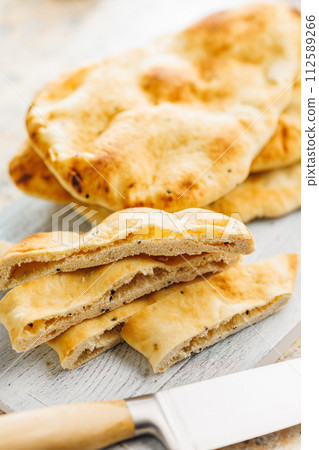Freshly Baked Naan Bread on citting board on kitchen table. 112589266