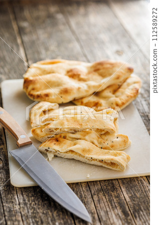 Freshly Baked Naan Bread on cutting board on wooden table 112589272