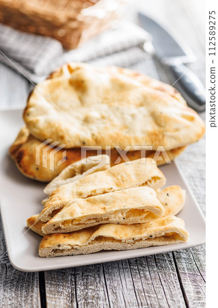 Freshly Baked Naan Bread on plate on wooden table Freshly Baked Naan Bread on plate on wooden table 112589275