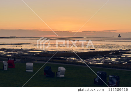 Dyke and beach chairs in the evening Dyke and beach chairs in the evening 112589416