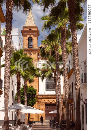 An old Catholic church against a backdrop of palm trees on a sunny day in Cadiz. An old Catholic church against a backdrop of palm trees on a sunny day in Cadiz. 112590025