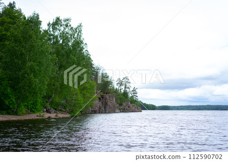Panorama of forest lake. Lake among the forest on a sunny summer day. Panorama of a lake in the woods. Panorama of a wild lake with a solid forest on the shores. 112590702