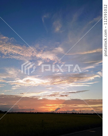 Summer sky and clouds colored orange by the setting sun on the horizon 112591012