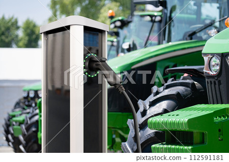 Electric vehicles charging station on a background of agricultural tractors. Concept.. 112591181