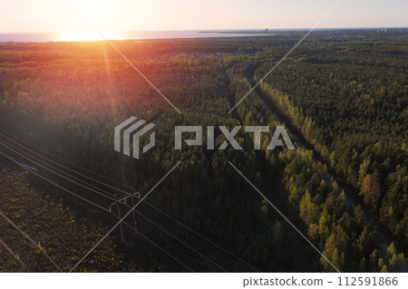 Smoking cooling towers at nuclear power plant and powerlines in forest. Sunset time. Aerial view Smoking cooling towers at nuclear power plant and powerlines in forest. Sunset time. Aerial view 112591866