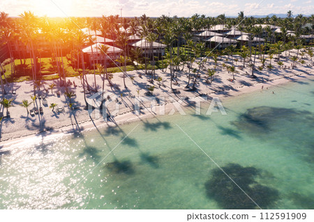 Sunset or sunrise on tropical beach with resorts, palm trees and caribbean sea. Dominican Republic. Aerial view 112591909