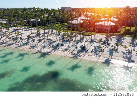 Sunset or sunrise on tropical beach with resorts, palm trees and caribbean sea. Dominican Republic. Aerial view 112592056