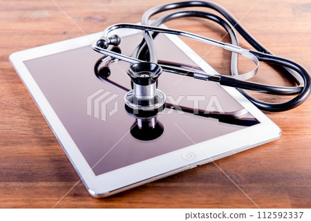 medical stethoscope and tablet on brown wooden background. Health care concept. phonendoscope. medical stethoscope and tablet on brown wooden background. Health care concept. phonendoscope. 112592337