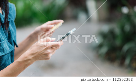 Close up view of a woman hands holding a credit card and a smartphone, likely engaging in an online transaction. 112592398
