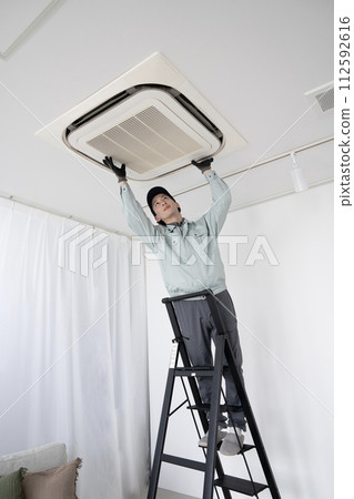 一名男工人正在檢查天花板上的空調 一名男工人正在檢查天花板上的空調 112592616