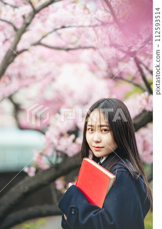盛開的櫻花下拿著紅書的女高中生 112593514