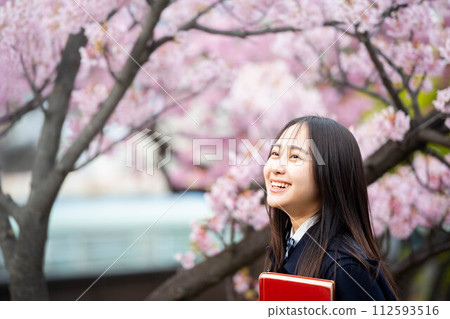 盛開的櫻花下拿著紅書的女高中生 112593516