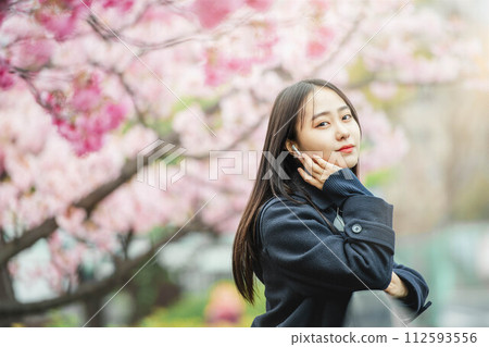 High school girls listening to music under cherry blossoms in full bloom 112593556