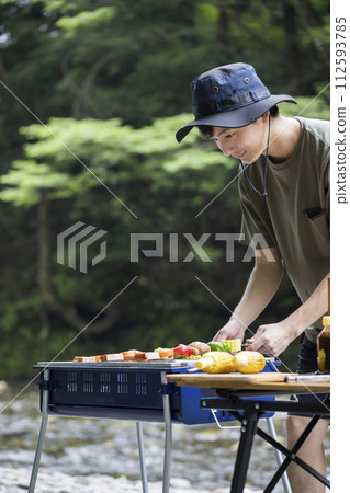 Barbecue image: Young man grilling skewers Barbecue image: Young man grilling skewers 112593785