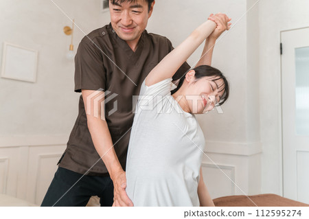 Patient and chiropractor doing traditional Thai massage, stretching, arm and shoulder massage Patient and chiropractor doing traditional Thai massage, stretching, arm and shoulder massage 112595274